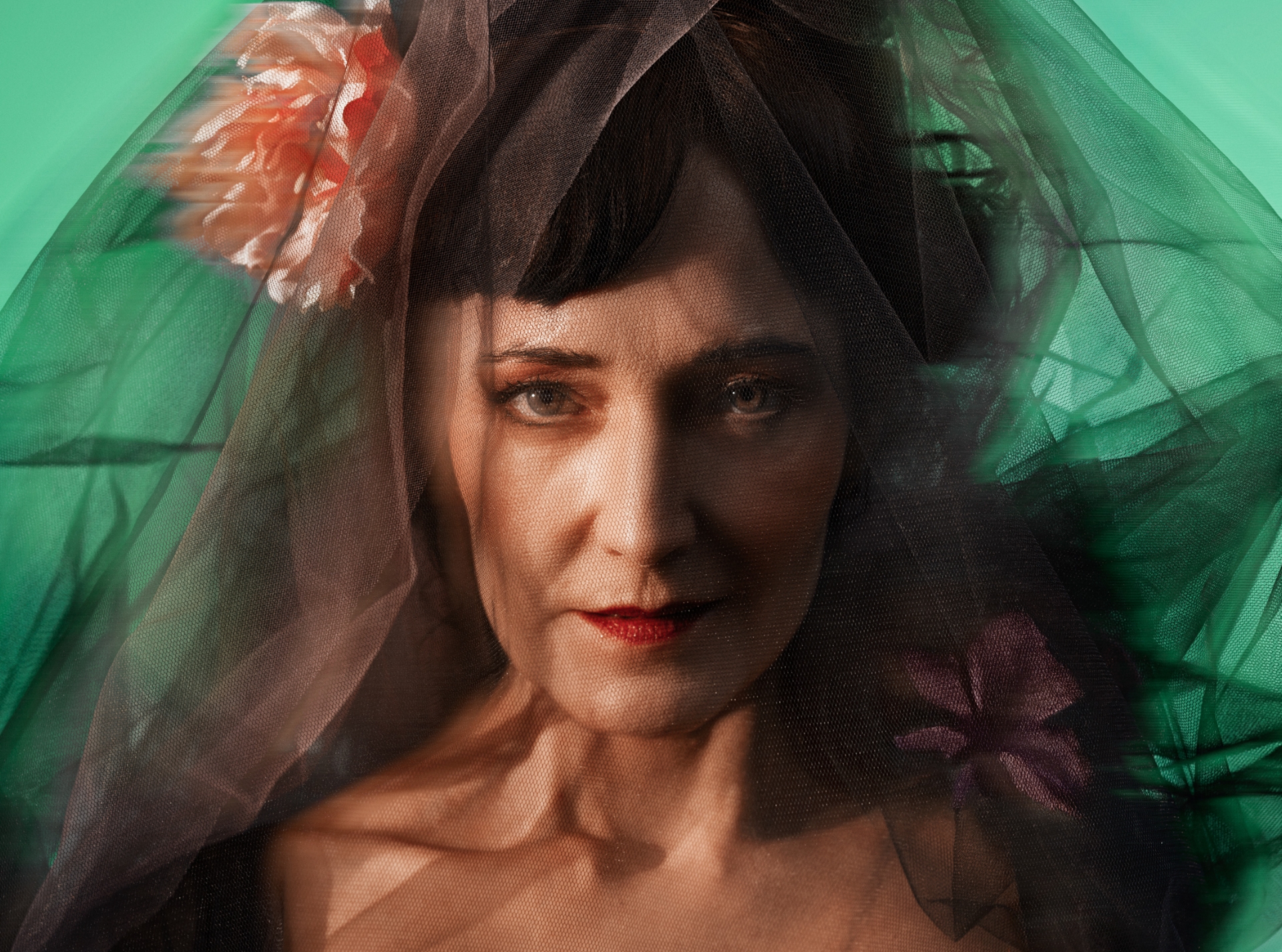 Portræt af mørkhåret kvinde med sort slør og en blomst i siden. Grøn baggrund. Fra forestillingen Fru Marie Grubbe på Odense Teater