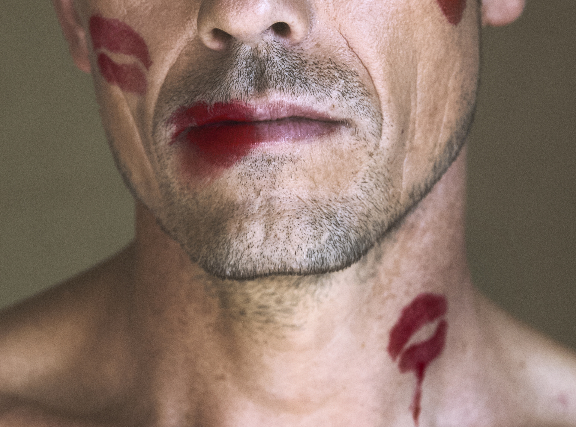 Mand med skægstubbe. Bar overkrop. Læbestiftkys på hals og i ansigt.