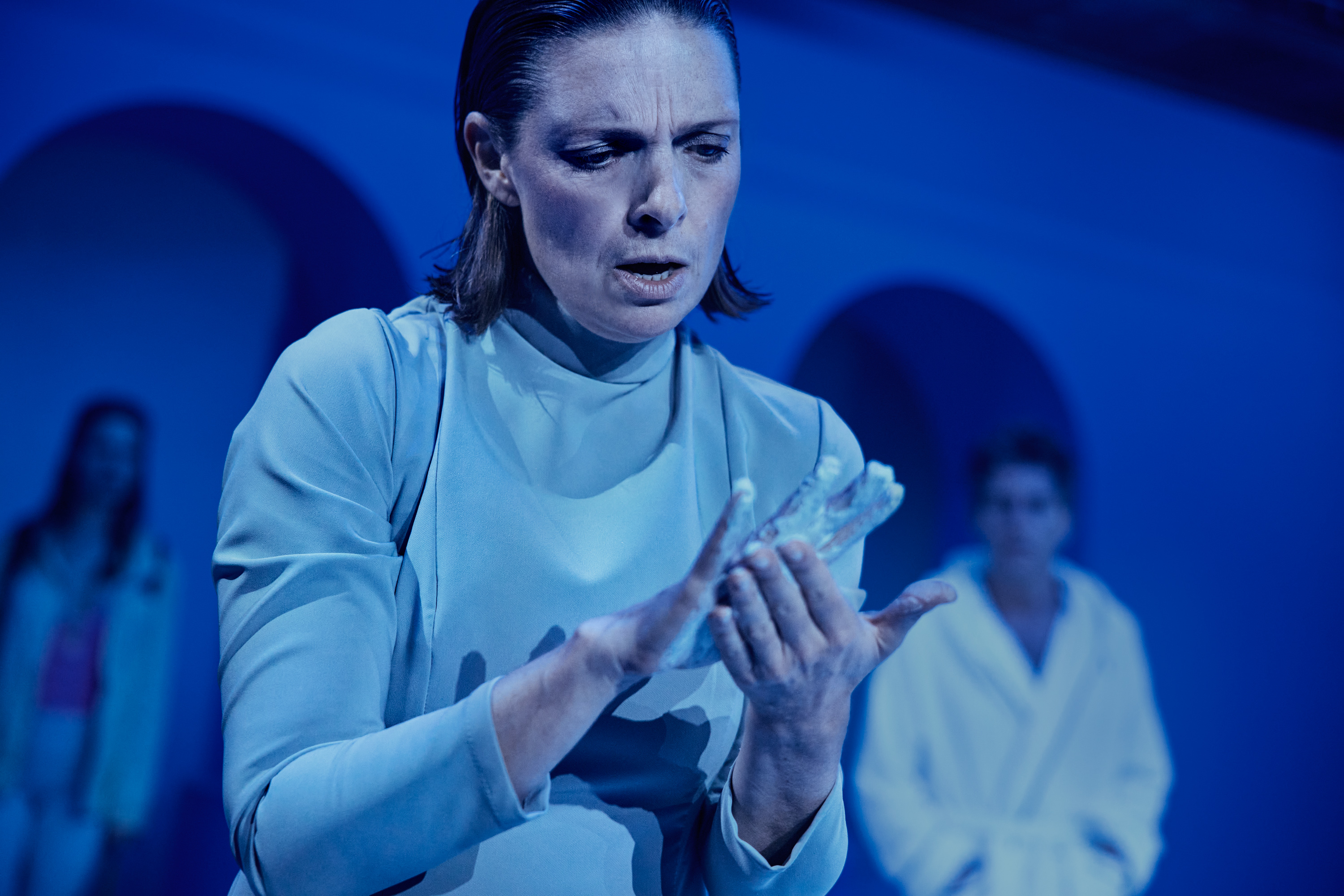en kvinde ser bekymret på sinde hænder der er smurt ind i noget hvidt. Fra forestillingen Når vi døde vågner på Odense Teater