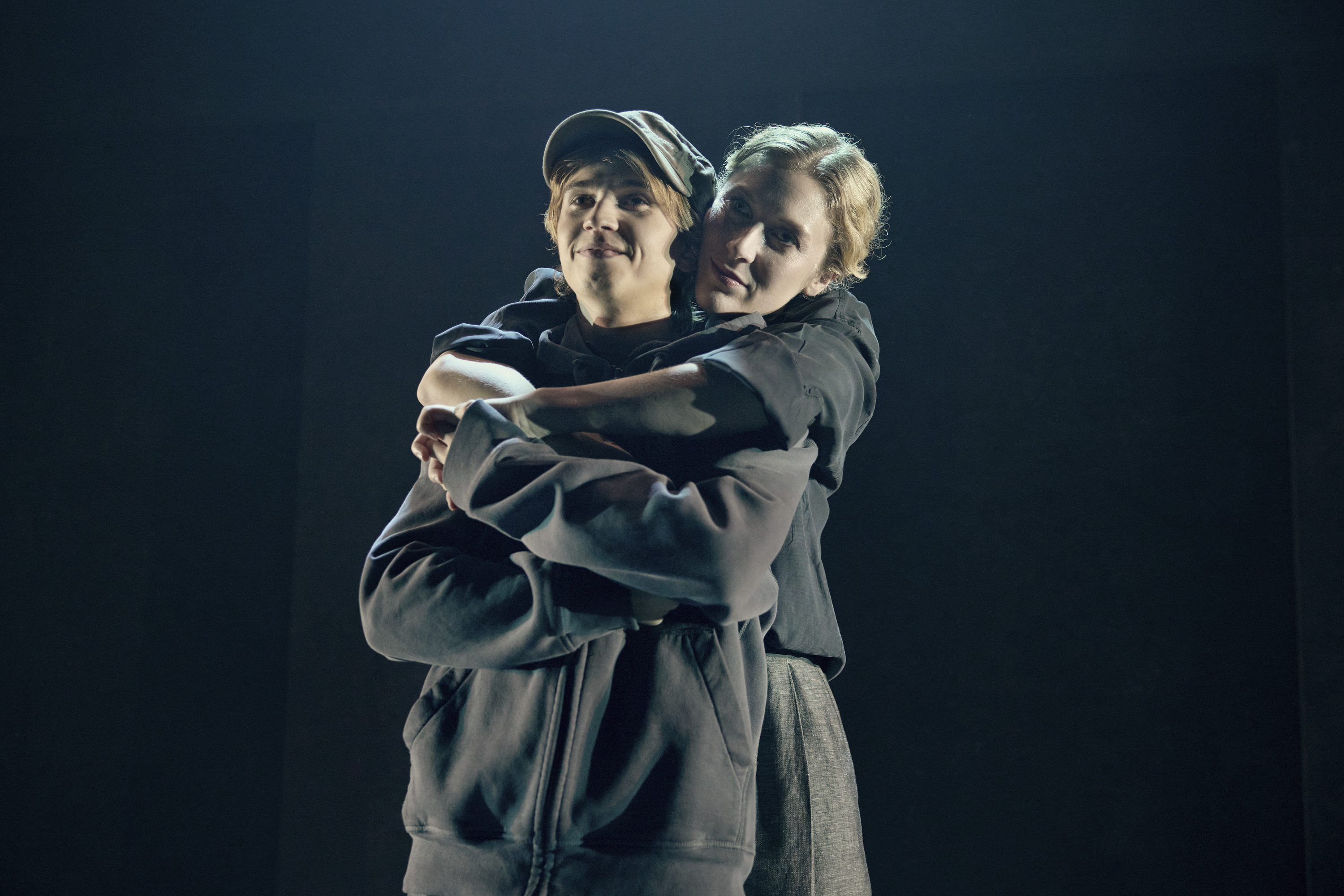 En kvinde omfavner en dreng bagfra i musicalen Next to Normal på Odense Teater