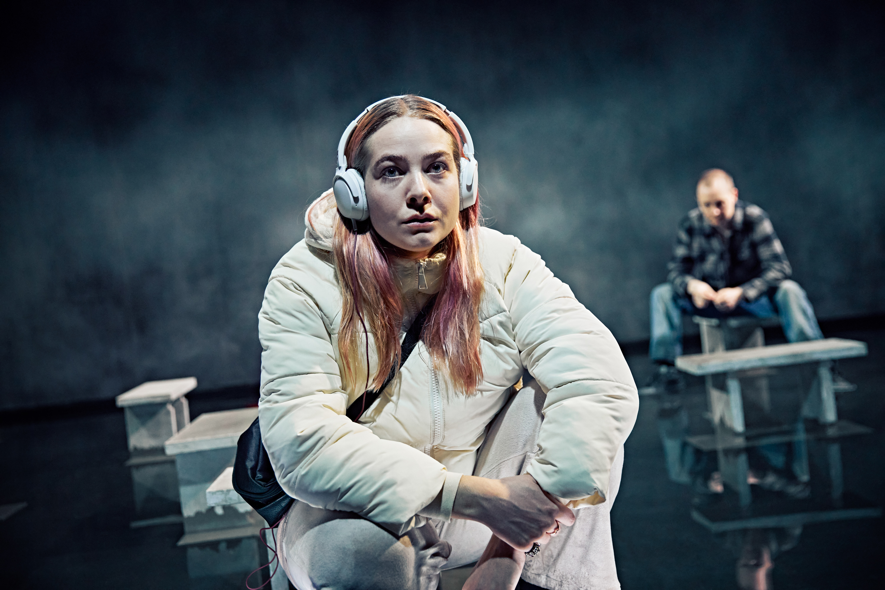 Ung kvinde med høretelefoner, langt hår og taske. Fra forestilling Maria på Odense Teater