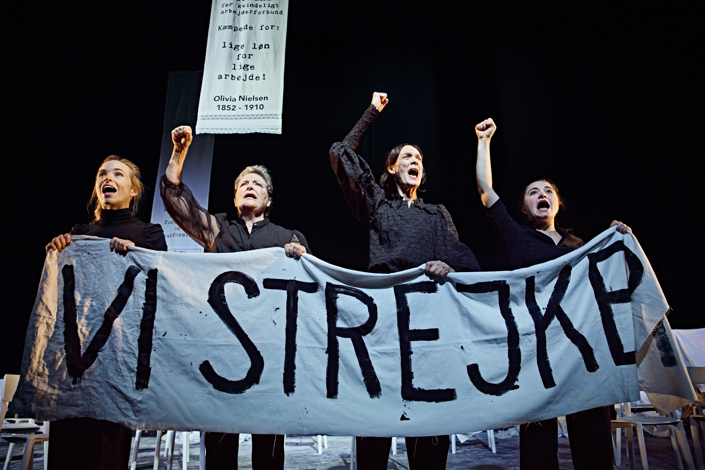 4 kvinder med banner Vi strejker. Fra forestilling Kvinde kend din historie på Odense Teater