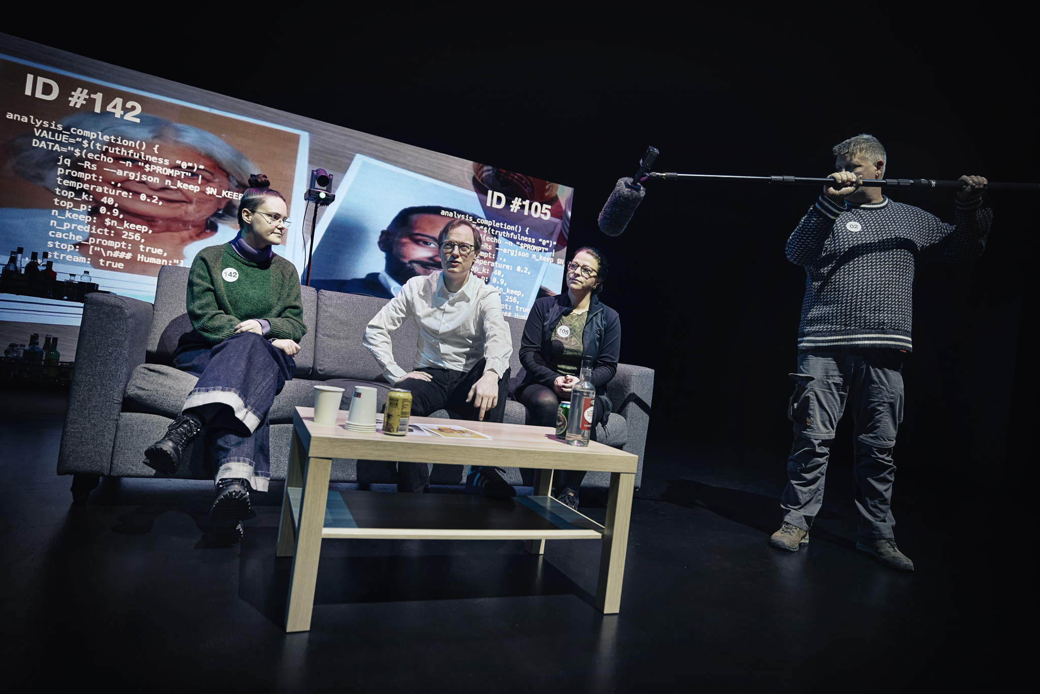 En mand og 2 kvinder i en sofa. Sofabord foran dem. En mand står ved siden af og holder en mikrofonstang. Fra forestillingen AI know you på Odense Teater