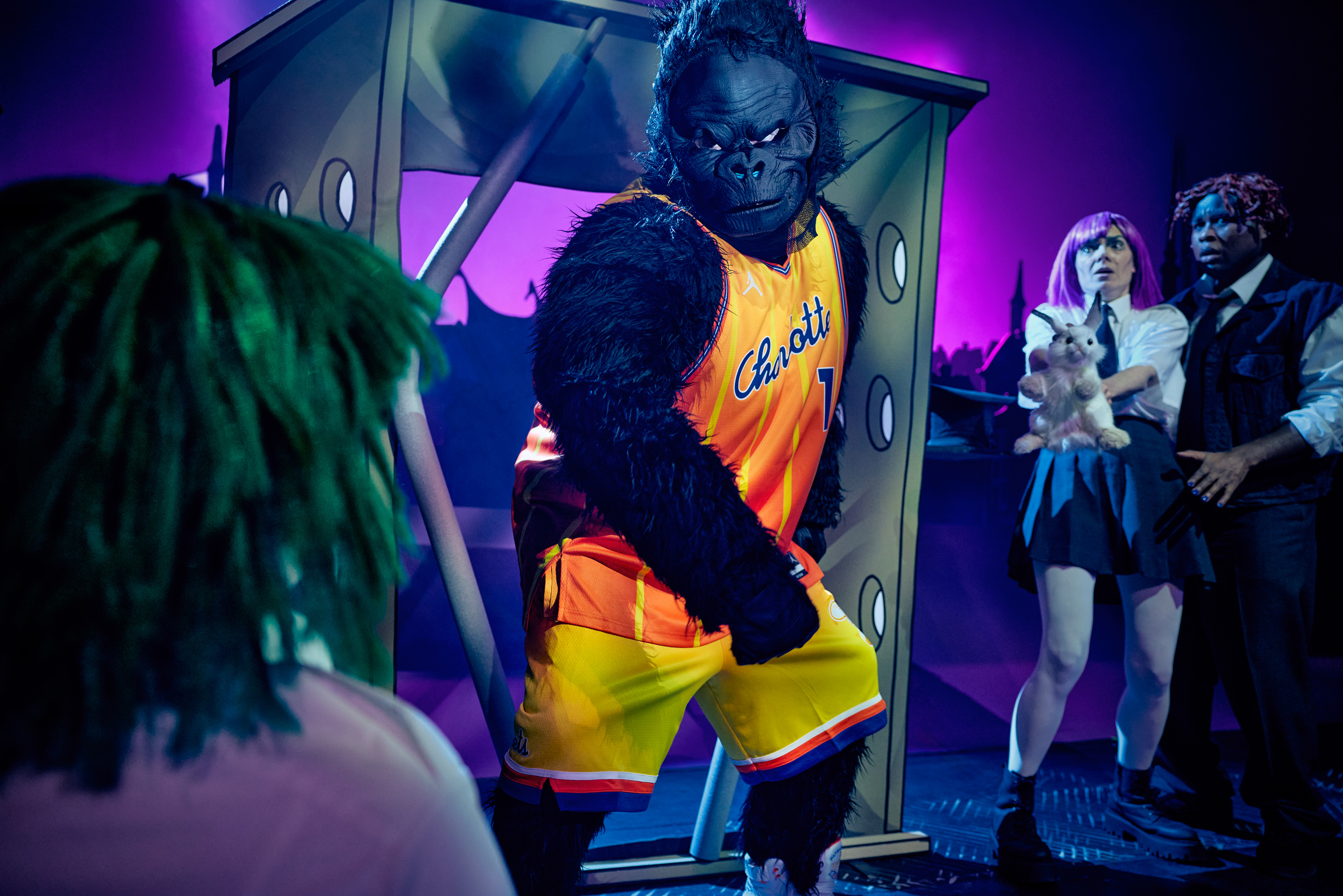 En stor gorilla i sportstøj bryder  ud af sit bur. 3 personer ser forskræmte på. Fra forestillingen Håndbog for superhelte på Odense Teater