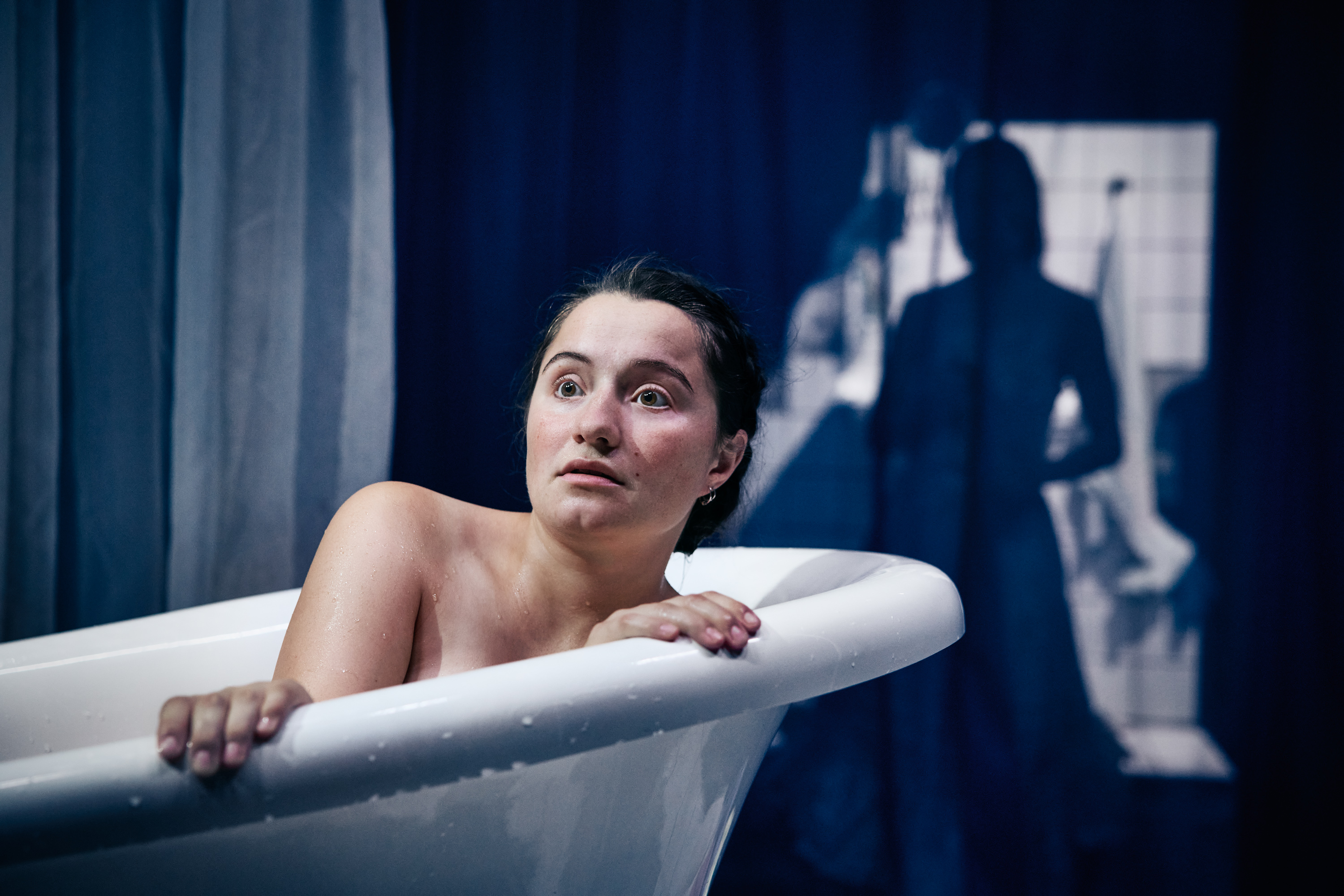 En nøgen kvinde i et badekar. Hun har et overrasket - måske forskræmt udtryk i ansigtet. Fra forestillingen Fruen fra havet på Odesense Teater. 