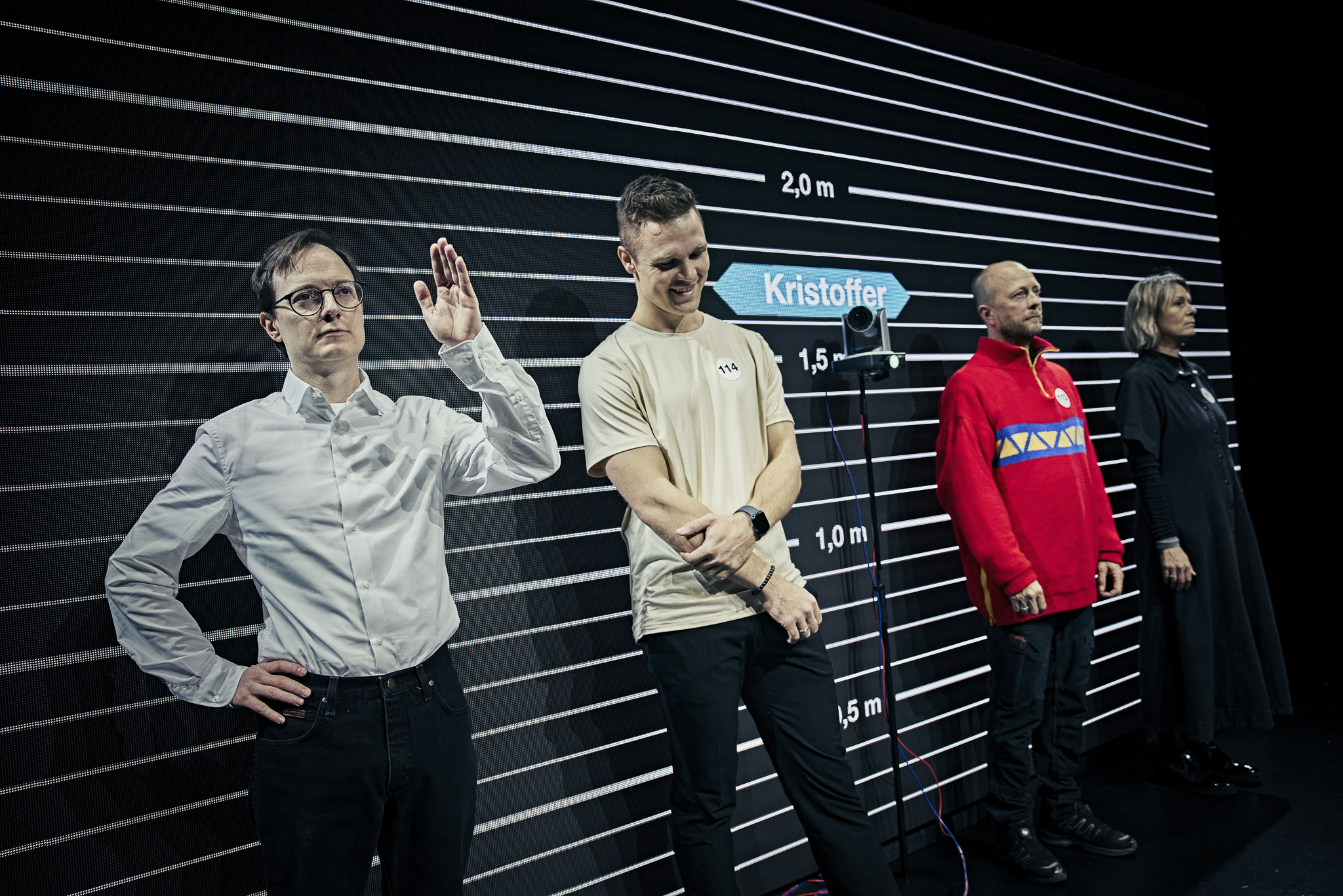 4 mennesker står foran en stor skærm med striber og tal. Fra forestillingen AI know you på Odense Teater
