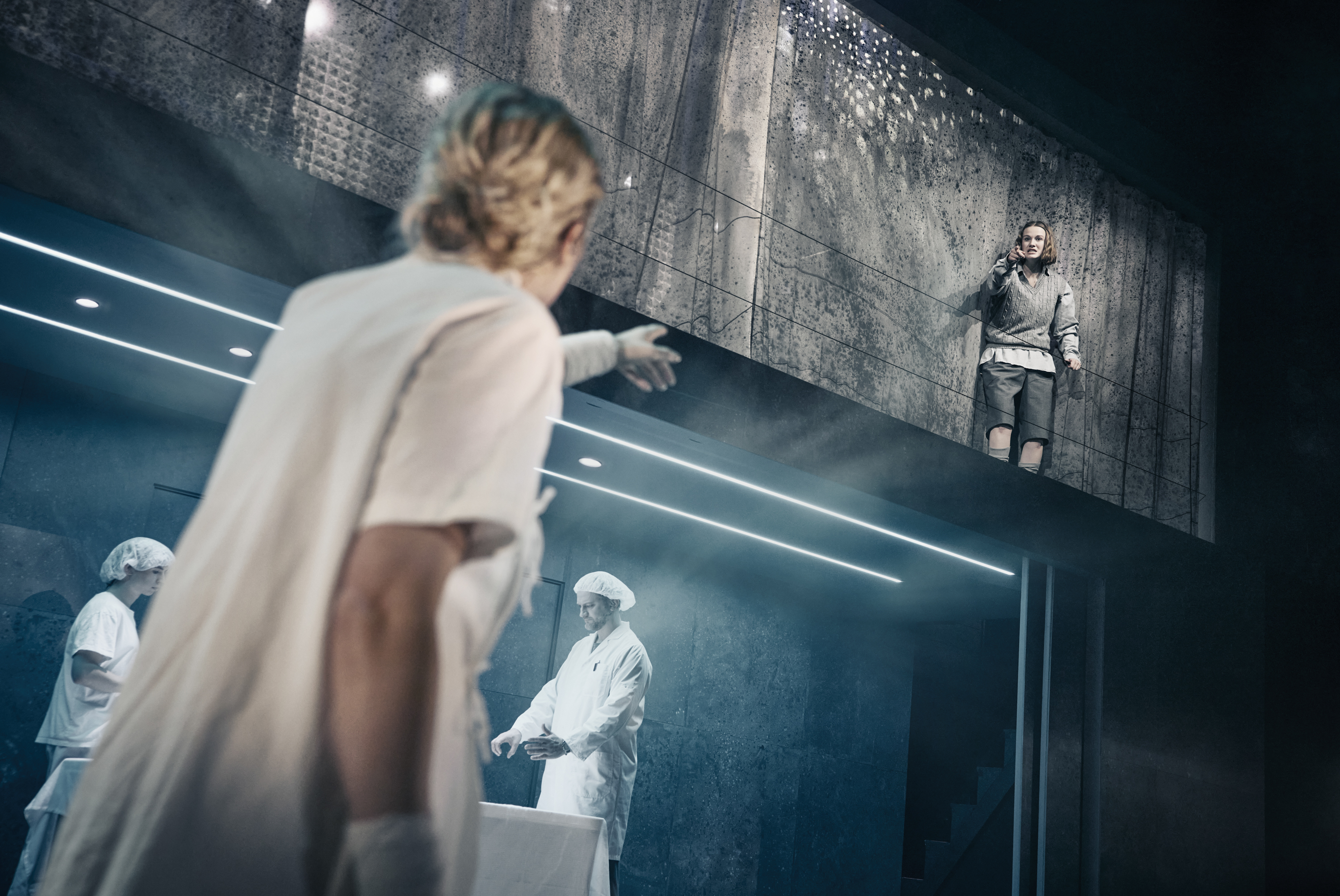 En kvinde i hospitalstøj peger mod en pige på balkon i musicalen Next to Normal på Odense Teater