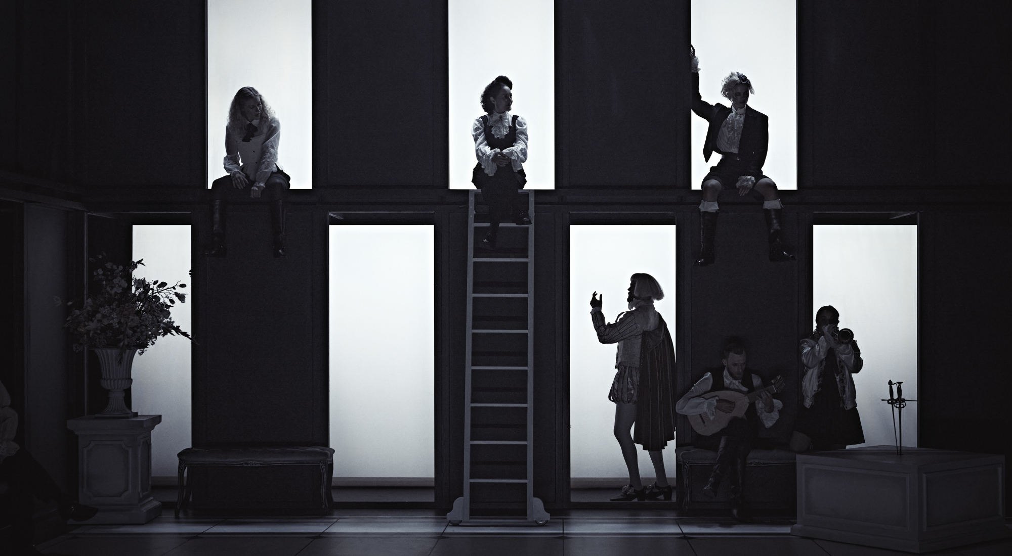 Sorte og hvide felter. Personer sidder i de hvide felter. Fra forestillingen Cyrano de Bergerac på Odense Teater