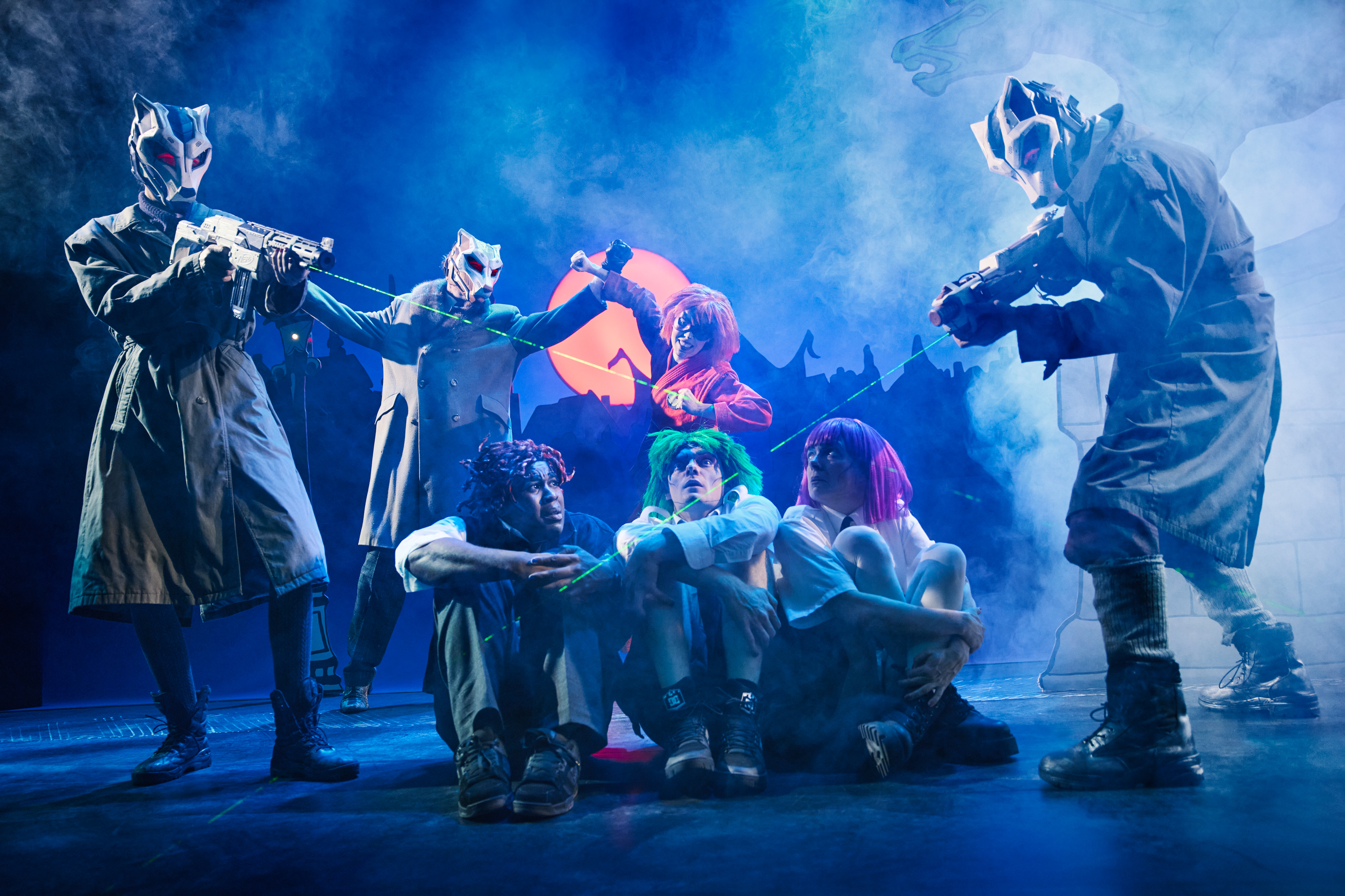 tre personer med lasergeværer og kampscener. 3 børn er taget til fange. Den røde superhelt kommer til undsætning. Fra forestillingen Håndbog for superhelte på Odense Teater