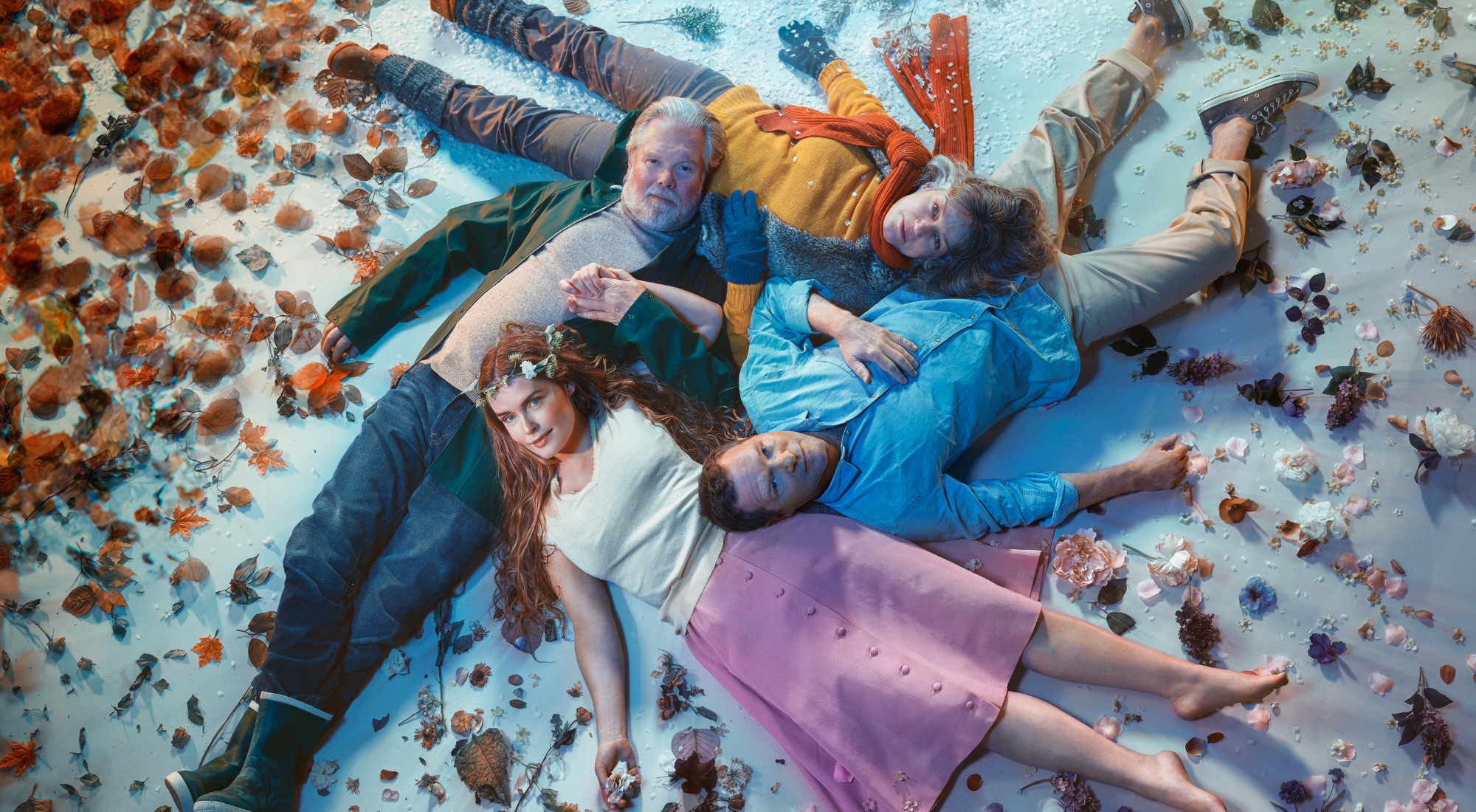 Billede taget oppefra og ned på 4 personer der ligger i rundkreds på gulv omgivet af blade og blomster. Fra forestillingen Alt i alt på Odense Teater