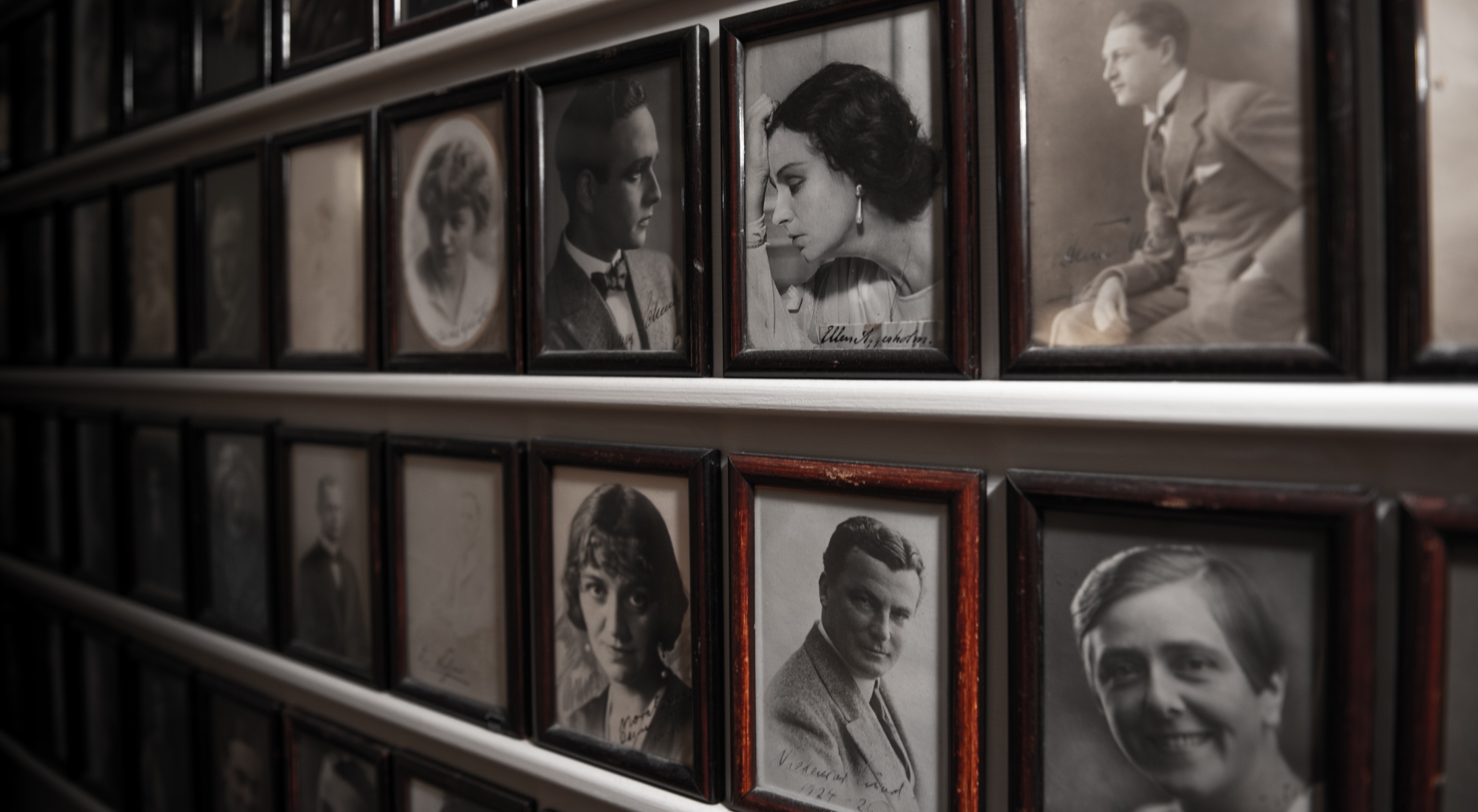 Gamle billedrammer på række med sort-hvide fotos af tidligere skuespillere på Odense Teater.