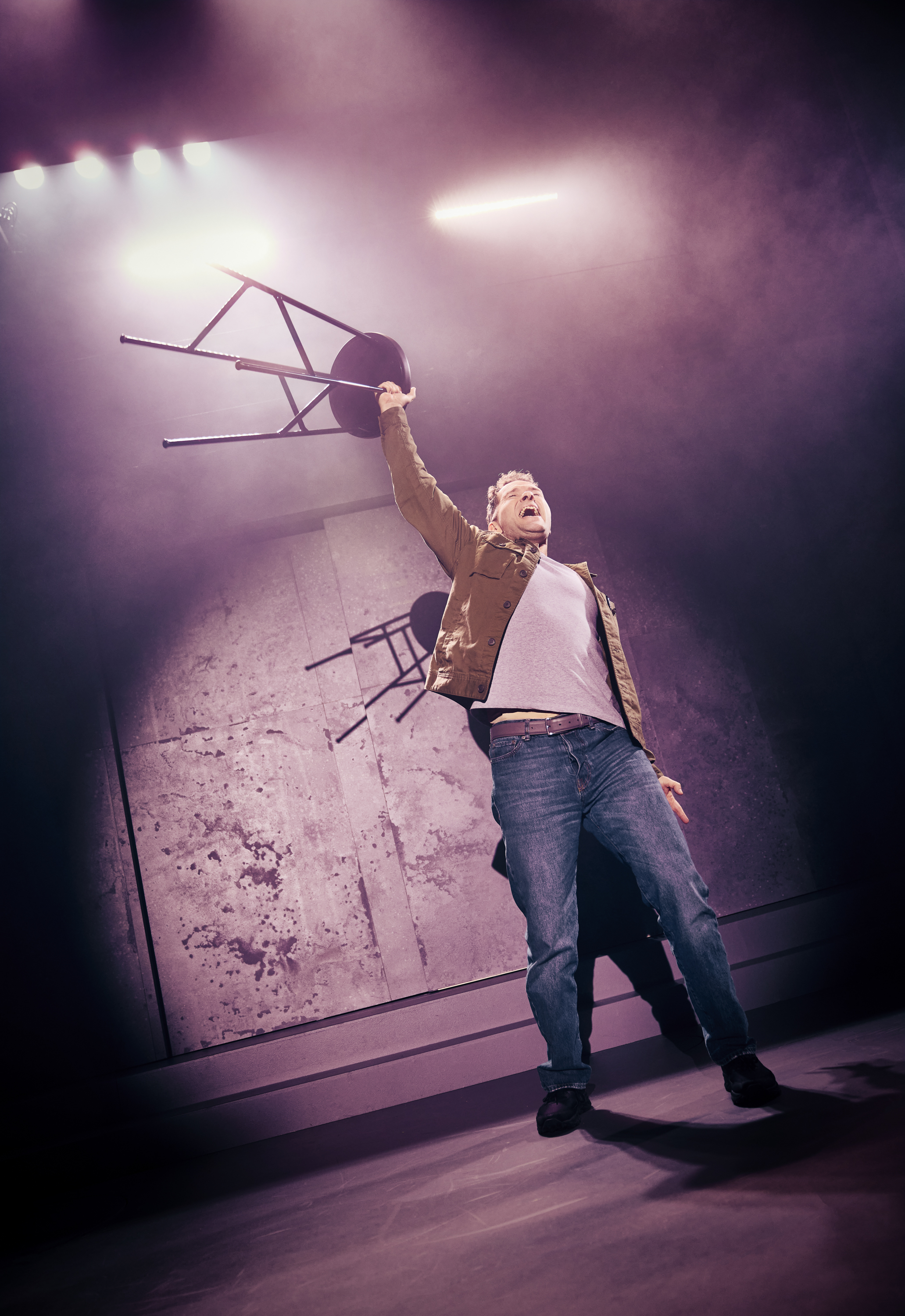 Mand løfter skammel op over hoved i en arm i musicalen Next to Normal på Odense Teater